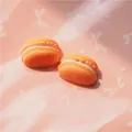 Macro shot of orange resin macaron charms with white cream filling for DIY crafts - Orange
