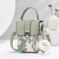 Retro paisley print handbag with green leather flap and plush monster charm on display - Green