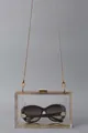 Transparent acrylic box clutch bag featuring a gold chain strap and metal clasp closure - Clear
