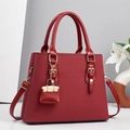 Dettaglio della trama bordeaux con finiture dorate e ciondolo decorativo per borsa - Rosso