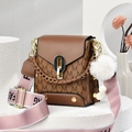 Brown vintage square handbag with M-letter print and pink fashion strap on white stand - Brown