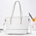 Détail du sac cabas blanc avec finitions dorées et fines poignées sur fond minimaliste - Blanc