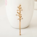 Eleganter goldener Haarclip mit Blattmotiv und Strasssteinen an einer weißen Tasse - Strass Ast KC Gold