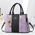 Dettaglio borsa a tracolla a righe viola con pelle nera e ciondolo a nappa colorato - Nero con Viola