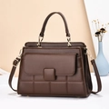 Sac à main en cuir marron foncé matelassé avec poignée et bandoulière dorée sur table - café