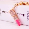 Sparkling lipstick keychain with pink accents and crystals on a white book surface - Deep Pink