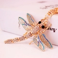 Enamel dragonfly keychain with crystals and blue-purple gradient wings on white book - Blue