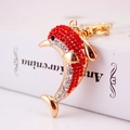 Golden dolphin keychain with red and clear rhinestones on a decorative white book - Red