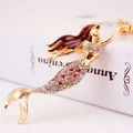 Sparkling rhinestone mermaid keychain with brown hair and red accents on book background - Red