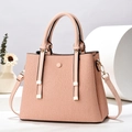Detail of pink pleated tote bag with golden hardware and detachable strap on white stand - Pink