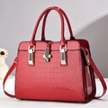 Close-up of red crocodile pattern patent leather handbag with gold metal clasp - Wine Red