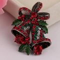 Détail d'une broche cloche de Noël avec strass rouges et feuilles en émail vert brillant - Argent Antique