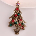 Close-up of vintage Christmas tree brooch with red and green rhinestones and star - Antique Gold