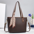 Close-up of brown lychee grain leather tote bag with elegant houndstooth scarf detail - Coffee