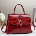 Detailed view of red crocodile-patterned patent leather tote bag with gold metal buckle - Red