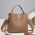 Close-up of tan lychee grain leather bucket bag with gold ring lock and woven strap - Khaki