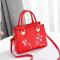 Nahaufnahme der roten Handtasche aus Lychee-Leder mit Blumenstickerei und Goldbeschlägen - Rot