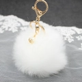 Dettaglio portachiavi a pompon bianco con chiusura dorata e perla su pizzo bianco - Bianco