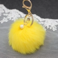 Dettaglio del portachiavi con pompon giallo in ecopelliccia e gancio dorato con perla - Giallo