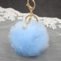 Vista macro portachiavi pompon blu con chiusura dorata e dettaglio perla decorativa - Celeste