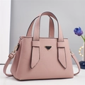 Detailed view of pink lychee leather texture and metallic triangle logo on handbag - Pink