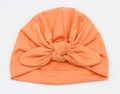 Detail of soft coral orange knitted baby turban hat featuring a large front bow knot - Coral Pink