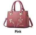 Pink lychee grain leather handbag featuring floral embroidery and golden crossbody strap - Pink