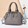 Close-up of grey litchi texture handbag with silver bear charm and tassel details - Gray