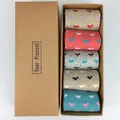 Close-up of five pairs of wool Christmas socks with heart patterns in a gift box - Heart Style