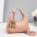 Detailed view of pink lychee leather handbag featuring a cute brown lion plush charm - Pink