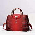 Detail of red crocodile pattern handbag with gold deer charm and metallic round handle - Burgundy