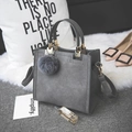 Close-up of matte grey crossbody bag with grey fur pompom and gold hardware accents - Gray