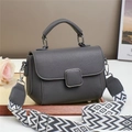 Deep grey litchi leather crossbody bag with wide geometric strap on a white surface - Gray