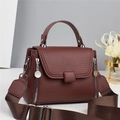 Deep brown pebble leather handbag with round top handle and wide fabric strap in studio setting - Brown