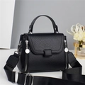 Detail of black pebbled leather handbag featuring silver zippers and adjustable wide strap - Black