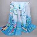 Dettaglio di sciarpa in chiffon blu con uccelli rossi e fiori appesa su barra - Celeste