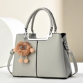 Elegant light gray pebbled leather handbag with silver hardware and lion plush charm - Gray