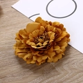 Detail shot of a dark yellow fabric peony flower accessory on a rustic wooden table - Gold