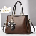 Detailed view of the dark brown PU leather texture and stylish bow pendant decoration - 30x13x22cm / Coffee