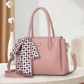 Pink lychee textured handbag with a plaid scarf and metal buckle detail on a stone table - Pink
