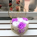 Purple and white soap roses in heart shaped gold wire basket on white bench - Purple + White