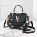 Schwarze Handtasche mit Gänseblümchen Stickerei, goldenem H-Verschluss und Anhänger - Schwarz