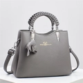 Macro shot of grey lychee leather handbag featuring a woven handle and charm - 26x12x20cm / Gray