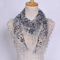 Détail d'un foulard en dentelle grise avec appliques florales argentées et pompons ronds - Gris foncé