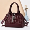 Elegant burgundy quilted dome bag with a bear charm and patterned crossbody strap - Wine Red