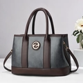 Borsa bicolore in pelle grigio scuro con manici marroni esposta su un supporto in pietra - Grigio