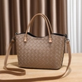 Brown woven leather handbag with top handle and adjustable shoulder strap on wooden table - Khaki