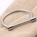 Polished silver stainless steel horseshoe D-shape bangle on textured linen background - Steel