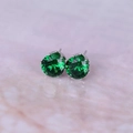 Macro view of forest green zircon stud earrings with classic silver-tone claw setting - Silver + Green