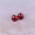 Macro detail of round red zircon stud earrings with silver crown setting on marble - Silver + Red